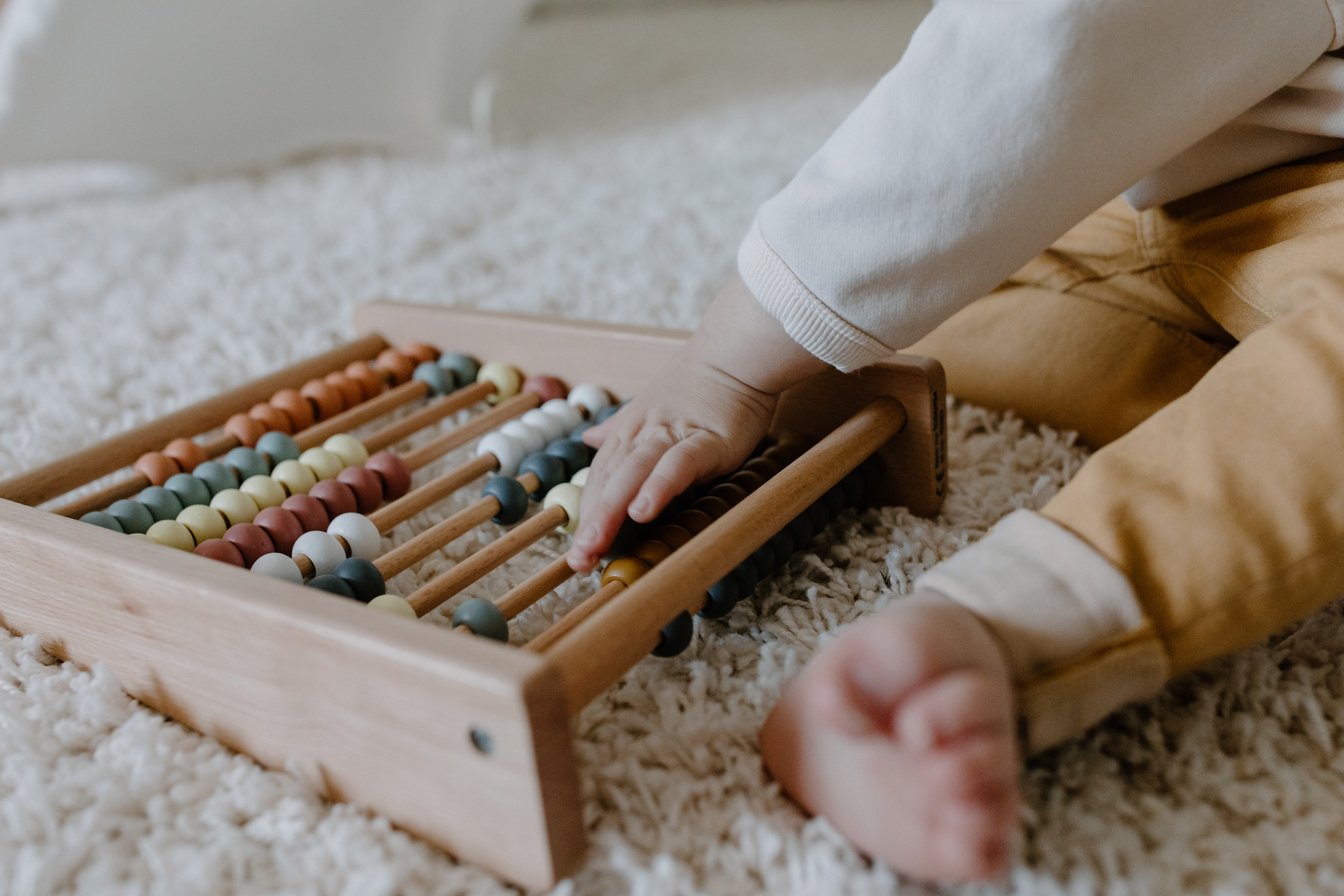 A Toddler Holding a Wooden Toy