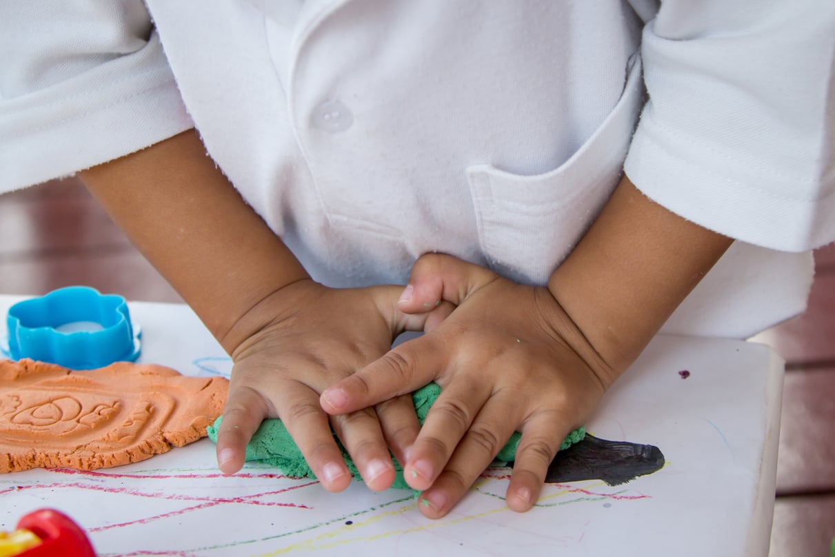 Child hand playing with clay, play doh